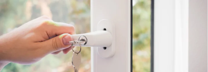 Hand schließt Fenster mit Schlüssel ab